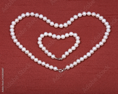 Freshwater white pearl necklace hearth shape on red fabric background