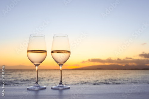 Pair of wine glasses on a bar at sunset. 