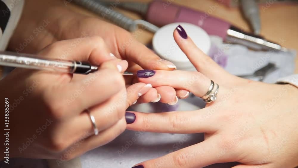 Manicurist paints woman's nails by brush, woman comes to the manicure salon, nail care, business in beauty Manicurist paints woman's nails by brush, woman comes to the manicure salon, nail care, business in beauty