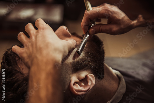 Men barber shaves his beard. photo