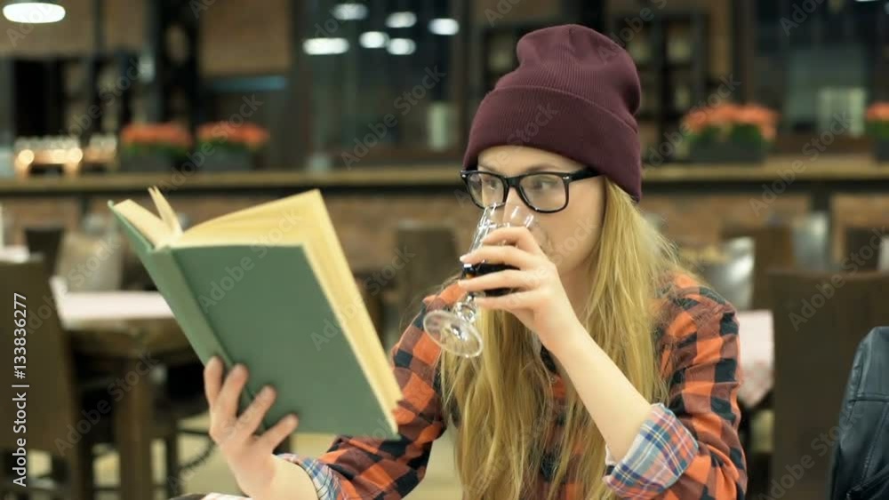 Hipster girl reading book and drinking beverage in the cafe, steadycam shot
Hipster girl reading book and drinking beverage in the cafe, steadycam shot