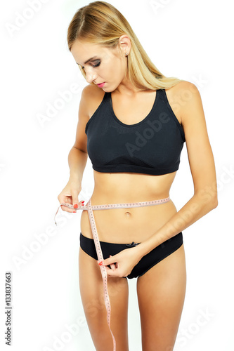 Young attractive woman measuring her hips