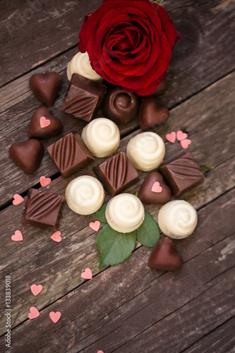Various chocolate pralines and red roses.