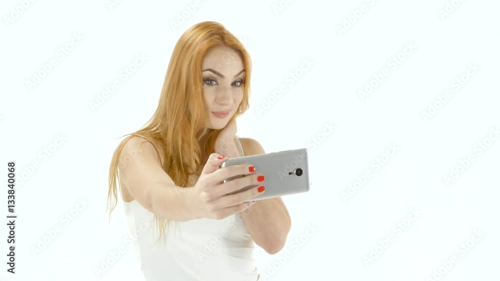 Redheaded girl model makes selfie photo on the mobile. Studio Redheaded girl model makes selfie photo on the mobile. Studio