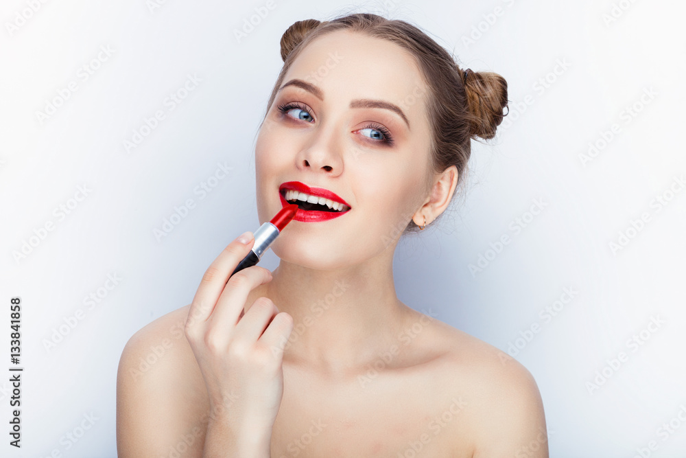Young pretty woman trendy makeup bright red lips bun hairstyle bare shoulders act the ape with lipstick white studio background Young pretty woman trendy makeup bright red lips bun hairstyle bare shoulders act the ape with lipstick white studio background