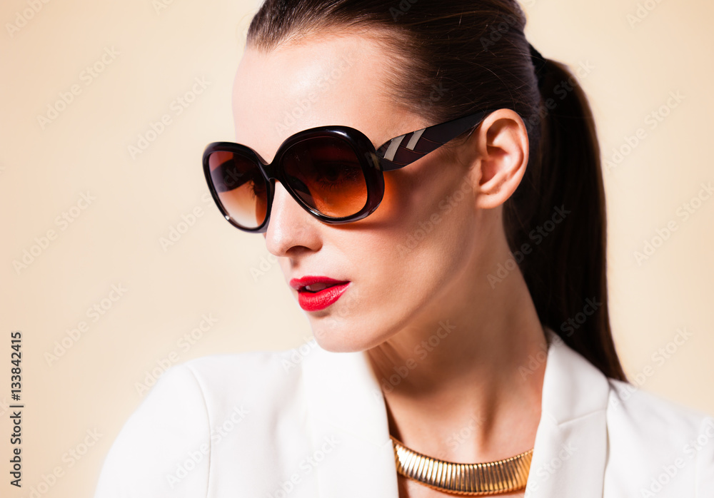Fashion portrait of attractive female wearing sunglasses and red lipstick. 