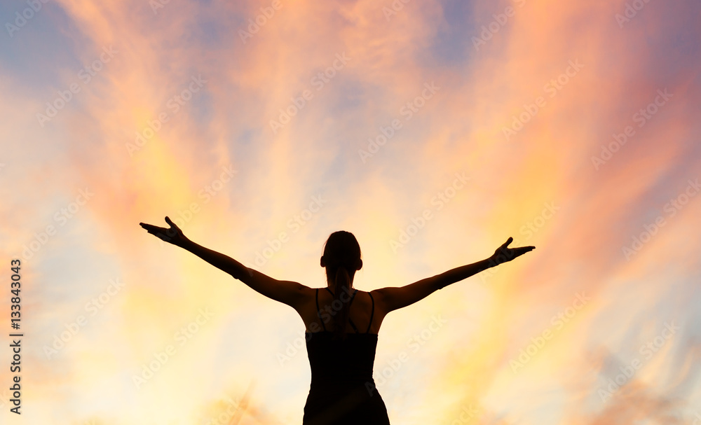 Happy woman with her arms out stretched into the sky. 