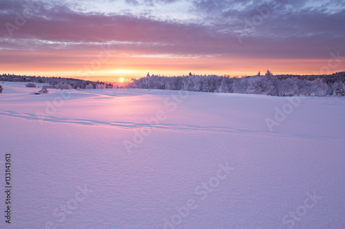 Wunderschöner Sonnenaufgang an einem kalten Wintertag im Erzgebirge mit einer kleinen Holzhütte im Hintergrund