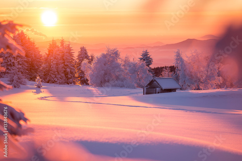 Fototapeta Wunderschöner Sonnenaufgang an einem kalten Wintertag im Erzgebirge mit einer kleinen Holzhütte im Hintergrund