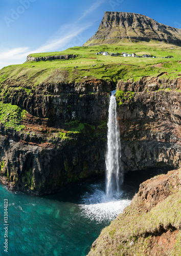 waterfall on faroe islands and the village Gasadalur in background