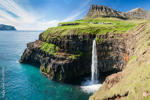 waterfall on faroe islands and the village Gasadalur in background