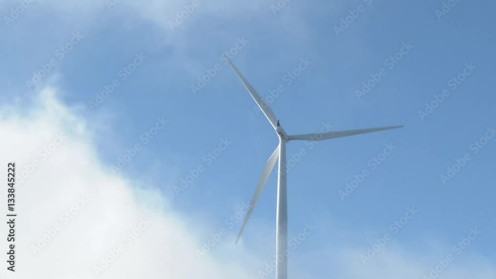 A large turbine spinning fast producing clean energy as wind picks up and clouds pass through frmae. A large turbine spinning fast producing clean energy as wind picks up and clouds pass through frmae.