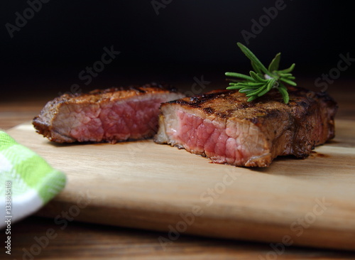  стейк  из говядины с розмарином на деревянной разделочной доске