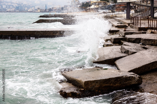 The waves break on the old jetty and the rocks. Autumn is overca photo