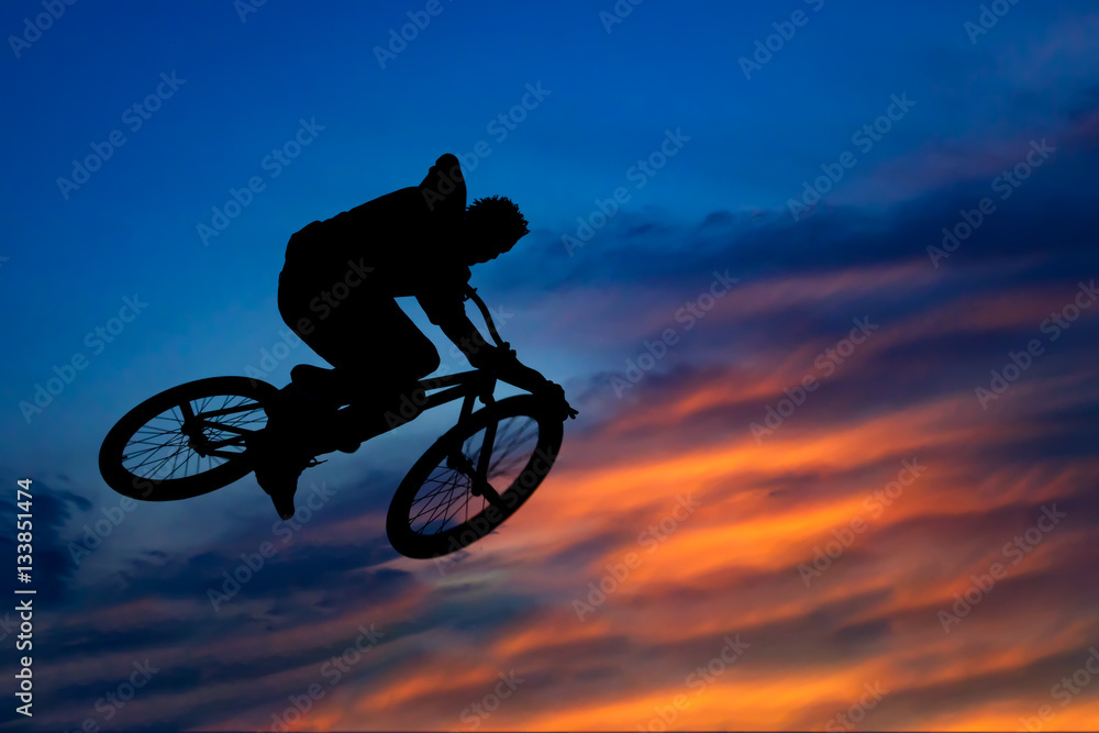 Silhouette of a biker jumping against the beautiful sky at sunse Silhouette of a biker jumping against the beautiful sky at sunse