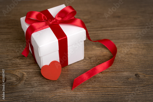 Gift box on the wooden background. Red ribbon. Valentine's Day gift. photo