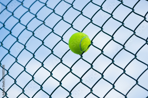 Tennis ball on metal wire against sky. Concept of tennis protection equipment