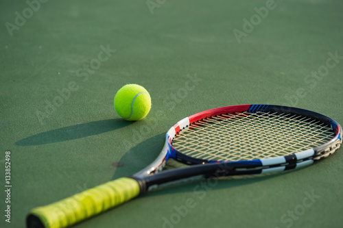 Tennis ball and racket under late evening sunlight