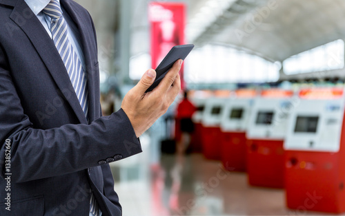 isolated business man hold the smartphone on airport background
