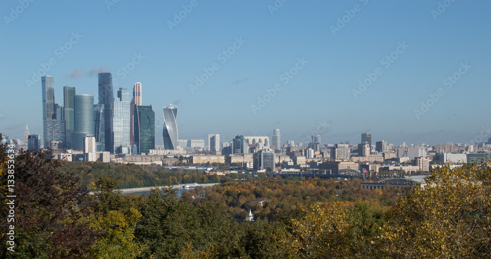 Obraz premium Moscow From Sparrow Hills with skyscrapers, office buildings and apartments in the distance and vegetation in the foreground.