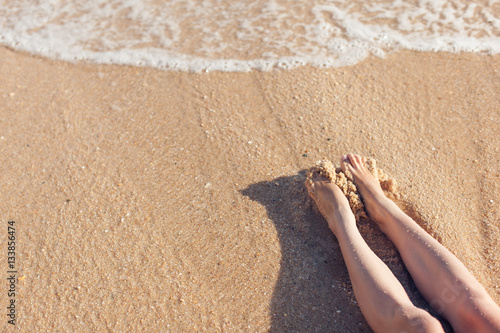 Feet girl in the sand on the beach near water