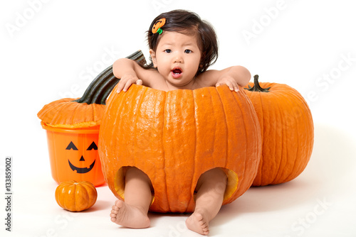 Baby girl in giant pumpkin for Halloween