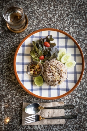 Mackerel fried brown rice with lemon, cucumber and tomato on marble table. photo