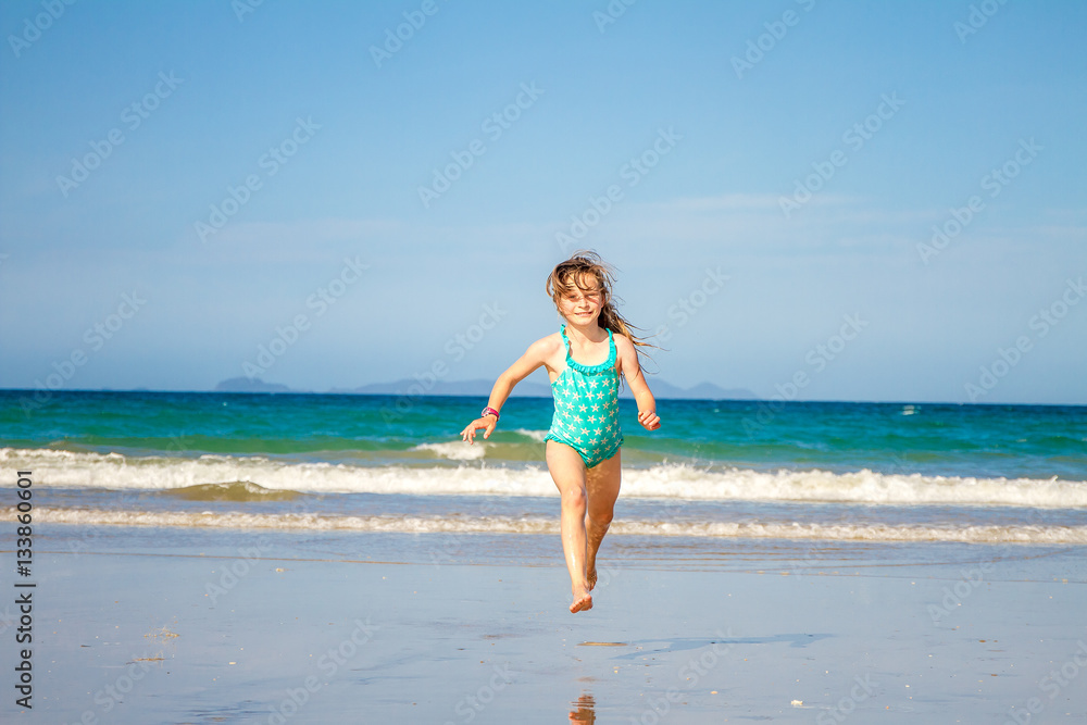 young happy child girl having fun on sand beach, sea background
