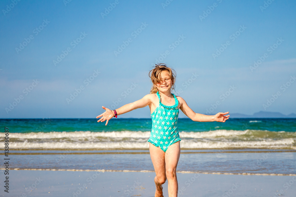 young happy child girl having fun on sand beach, sea background young happy child girl having fun on sand beach, sea background