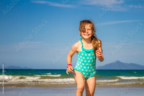 young happy child girl having fun on sand beach, sea background