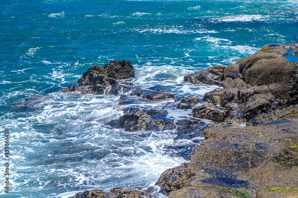 The waves breaking on a stony beach, forming a spray The waves breaking on a stony beach, forming a spray