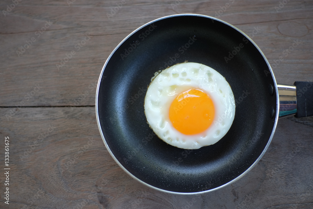 fried egg with pan on wood floor fried egg with pan on wood floor