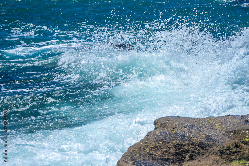 Obraz premium The waves breaking on a stony beach, forming a spray