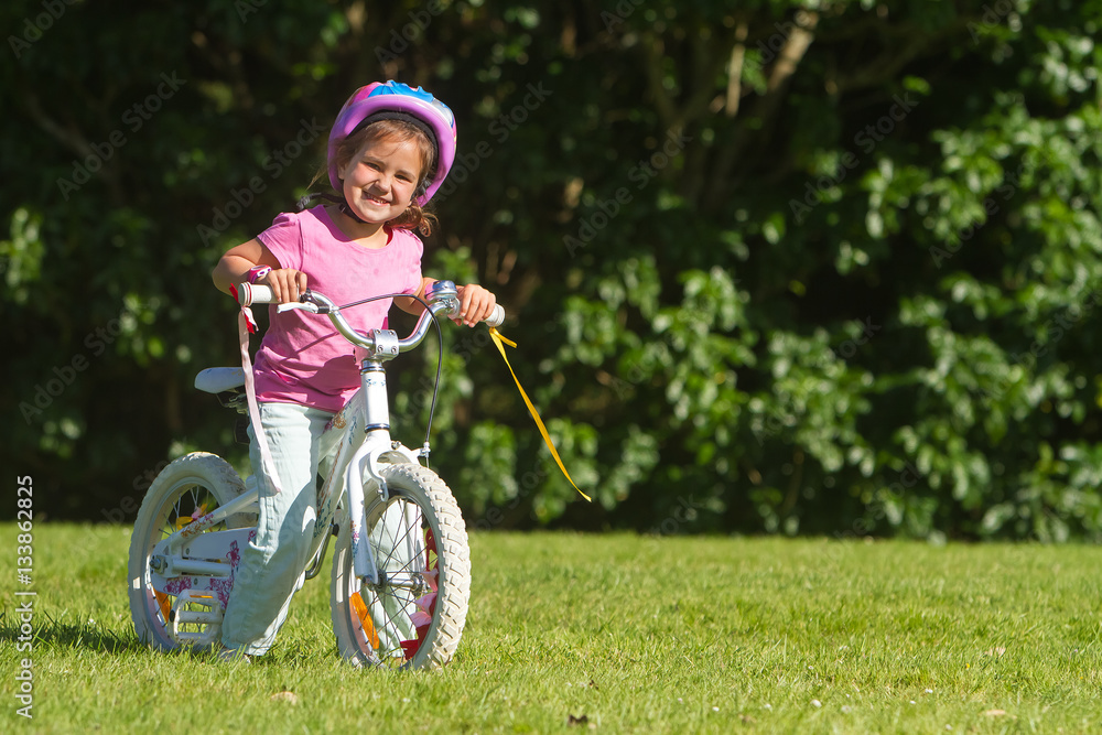 outdoor portrait of young happy child girl riding a bike in park outdoor portrait of young happy child girl riding a bike in park