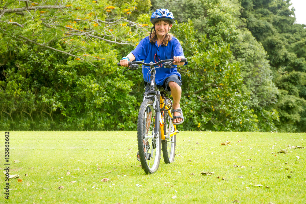 Naklejka premium young happy preteen child boy riding a bicycle on natural park b