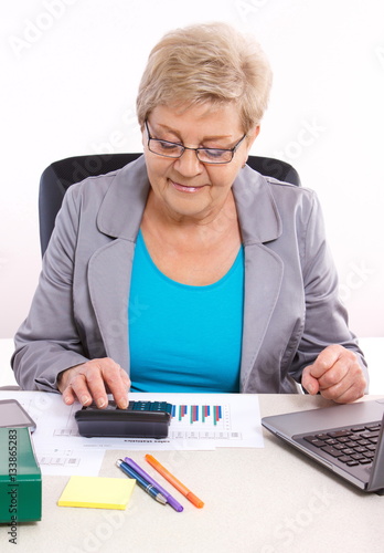 Elderly business woman working at her desk in office, analysis of sales plan, business concept