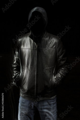 Mystic black hooded man standing in the darkness.