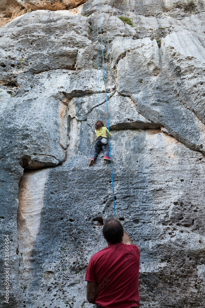 Little girl climbing on a limestone wall