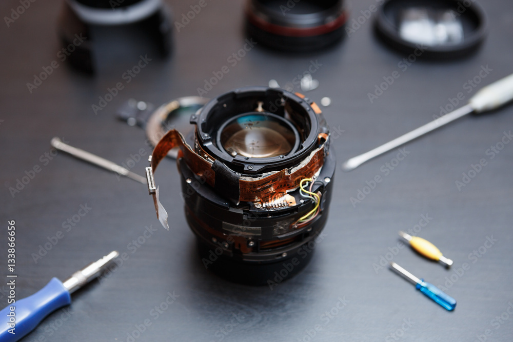 Broken dslr camera lens repair in service center. Dissassembled lens for  professional photo camera and tools for repairs Stock Photo | Adobe Stock