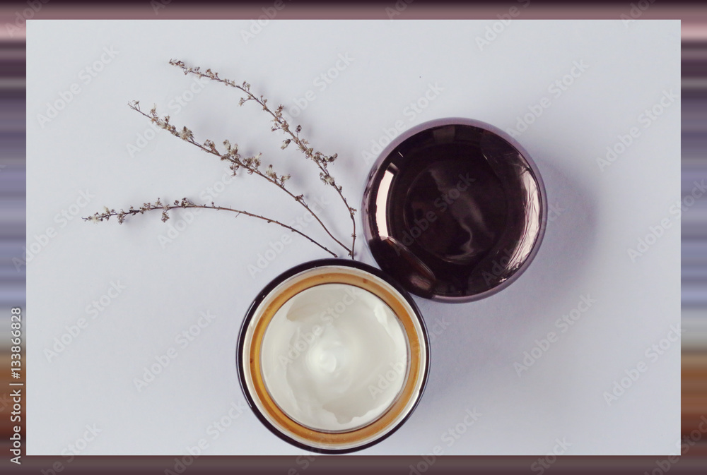 Serum in sackcloth, cream and dried herbs on a light background in blurred striped frame. organic cosmetics concept Serum in sackcloth, cream and dried herbs on a light background in blurred striped frame. organic cosmetics concept