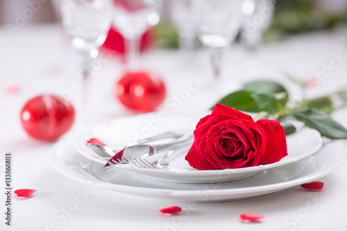 Table setting for valentines or wedding day with red roses. Romantic table setting for two with roses plates cups and cutlery.