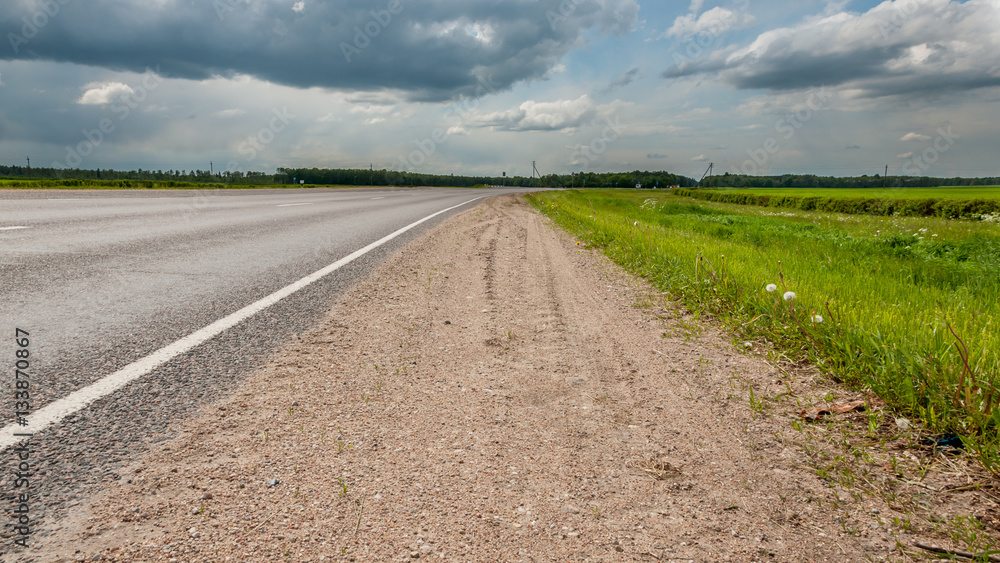 rural landscape. non urban asphalt road, green meadow, beautiful cloudy sky rural landscape. non urban asphalt road, green meadow, beautiful cloudy sky