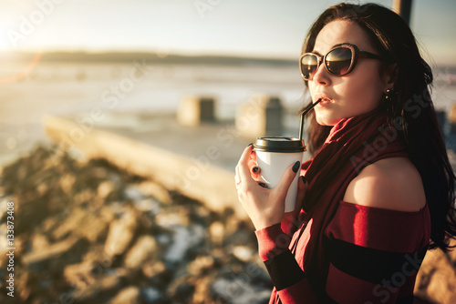 brunette girl walk outdoor in the park with cup of coffee
