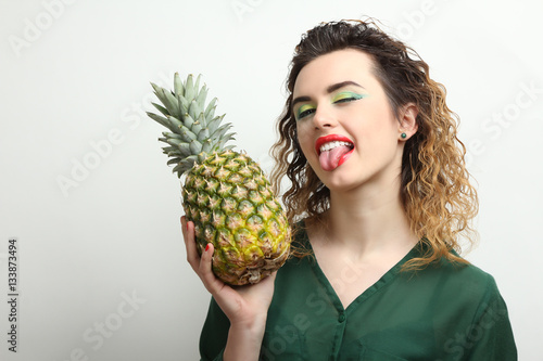 Cheerful girl model holding a pineapple.