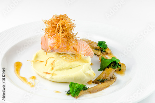 Salmon with mashed potatoes and gravy on a plate on a white background, closeup