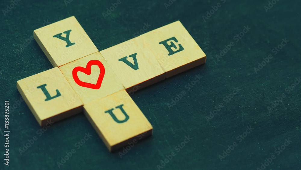 Letters spelling LOVE YOU and red heart on chalkboard with selective focus and vintage color tone Letters spelling LOVE YOU and red heart on chalkboard with selective focus and vintage color tone