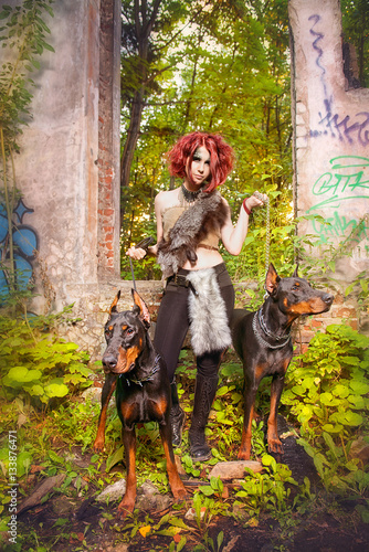 Girl Amazon with Dobermans in the ruins of an old house