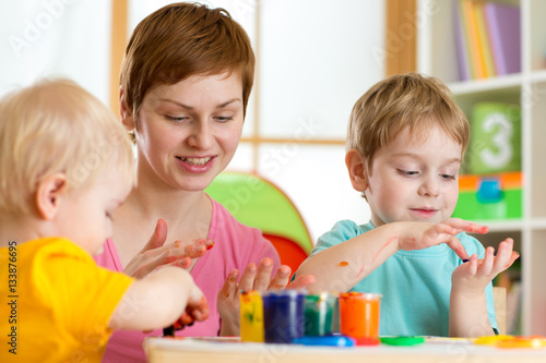 Kids with teacher painting in playschool