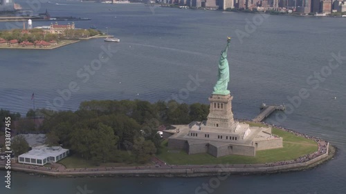 AERIAL: Flying around Statue of Liberty in front of downtown New York city