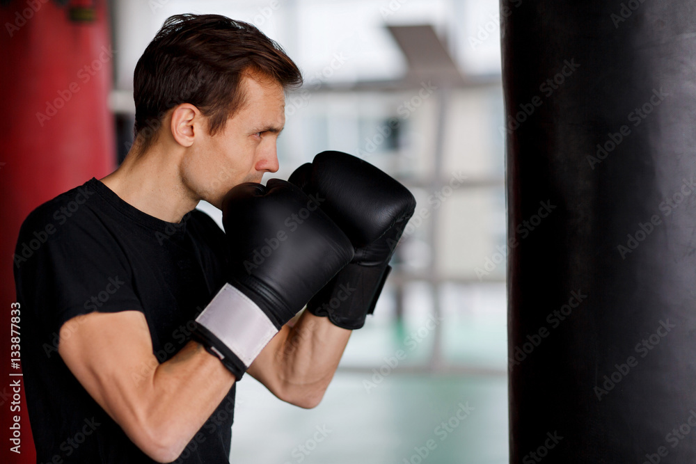 Young sportsman in boxing bag